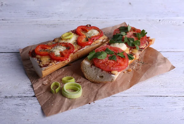 Sabroso sándwich con verduras y queso sobre papel sobre fondo de madera — Foto de Stock