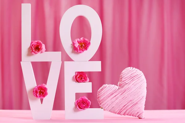 Letras decorativas formando palabra AMOR con flores sobre fondo rosa — Foto de Stock