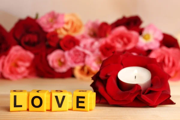 Letras decorativas formando palabra AMOR con flores y vela sobre fondo brillante —  Fotos de Stock