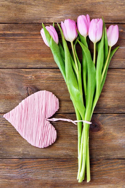 Hermosos tulipanes rosados con corazón decorativo sobre fondo de madera — Foto de Stock