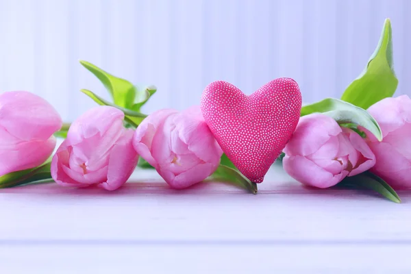 Beautiful pink tulips with decorative heart on wooden background — Stock Photo, Image