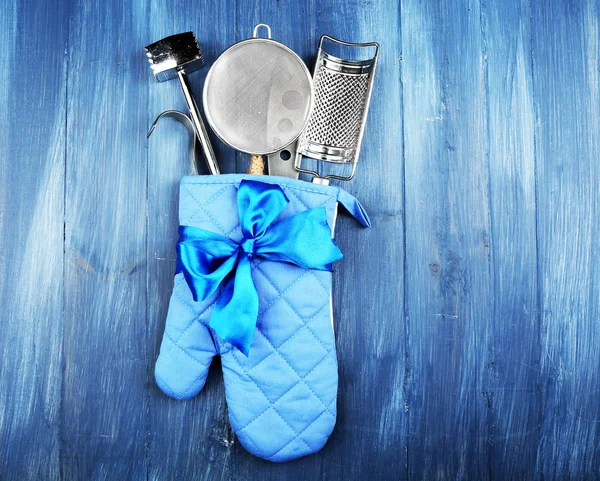 Different kitchen utensils in potholder on wooden background — Stock Photo, Image