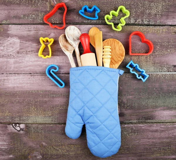 Different kitchen utensils in potholder on wooden background — Stock Photo, Image