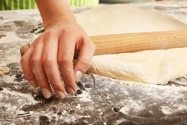Making dough by female hands on wooden table background