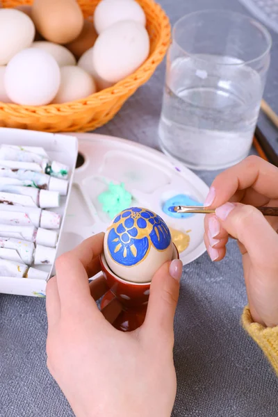 Peinture des œufs de Pâques par des mains féminines sur fond de nappe colorée — Photo