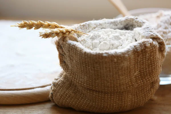 Flour in burlap bag with cutting board on wooden background — Stock Photo, Image