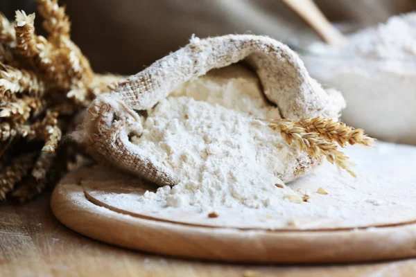 Flour in burlap bag on cutting board and wooden table background — Stock Photo, Image