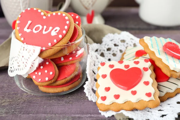 Soubory cookie pro valentinky den, konvice a šálky na barevné dřevěné pozadí ve tvaru srdce — Stock fotografie