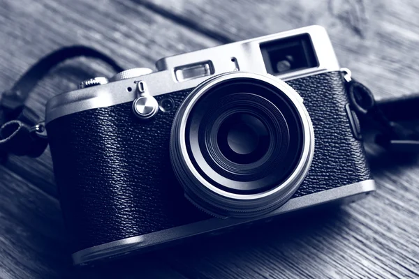 Retro camera op houten tafel in schaduwen van grijs, close-up — Stockfoto