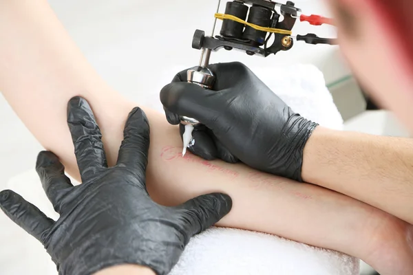 Tattooer showing process of making tattoo, close up — Stock Photo, Image