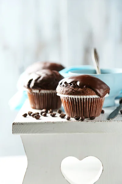 Chutné domácí čokoládové muffiny a šálek kávy na dřevěný stůl, na světlé pozadí — Stock fotografie