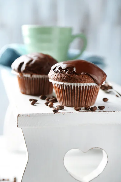 Tasty homemade chocolate muffins and cup of coffee on wooden table, on light background — Stock Photo, Image