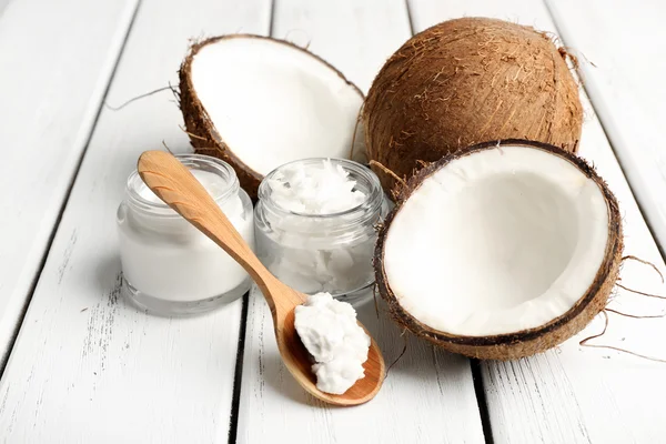 Coco con frascos de aceite de coco y crema cosmética sobre fondo de madera — Foto de Stock