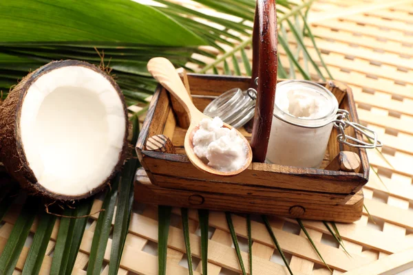 Coco con hojas y aceite de coco en frasco sobre fondo de madera —  Fotos de Stock