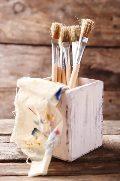 Paint brushes on old wooden background — Stock Photo, Image