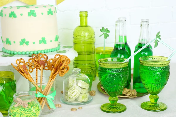 Composition for St Patrick Day with sweets and drinks on table on brick wall background — Stock Photo, Image