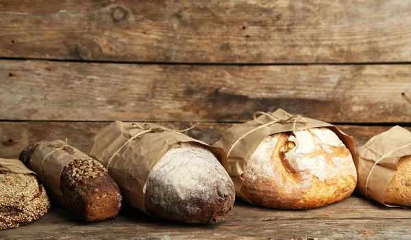 Different fresh bread, on old wooden table — Stock Photo, Image