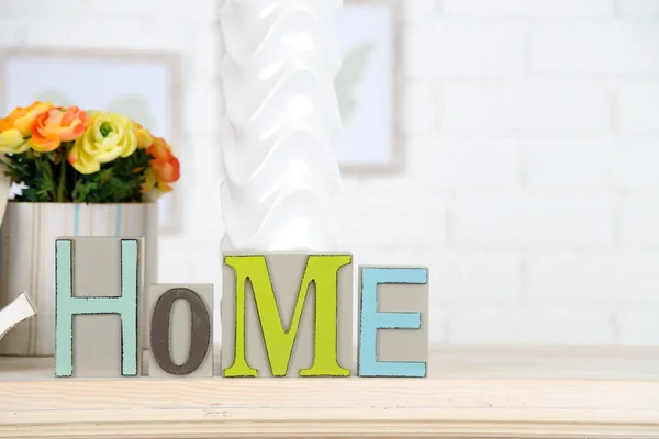 Casa en letras de colores, en el interior blanco claro, en estante de madera — Foto de Stock