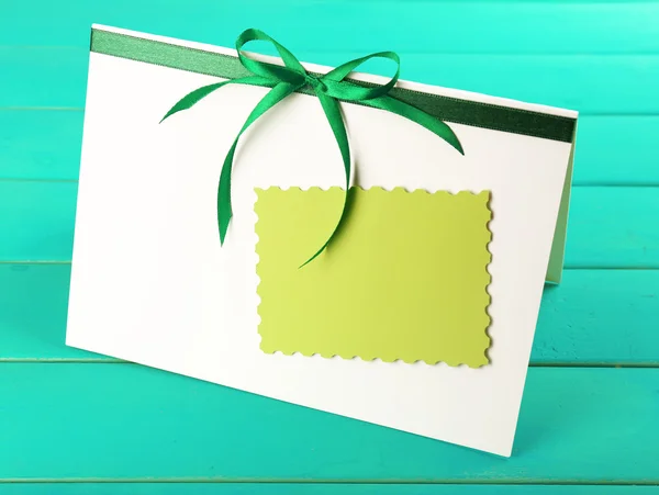 Card decorated with green bow on wooden background — Stock Photo, Image