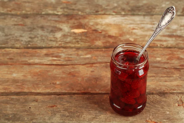 Pot de confiture de fraises avec cuillère sur fond en bois — Photo