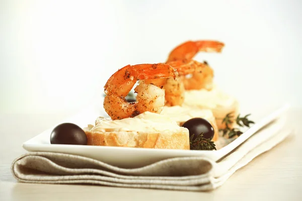 开胃菜烤面包片虾仁和橄榄上浅色背景表格 — 图库照片