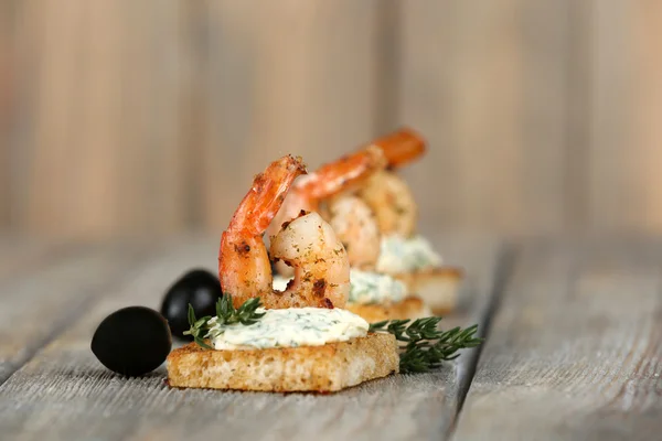 Voorgerecht canapé met garnalen en olijven op houten achtergrond — Stockfoto