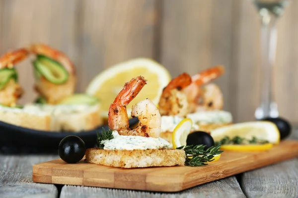 Appetizer canape with shrimp and olives on cutting board on table close up — Stock Photo, Image
