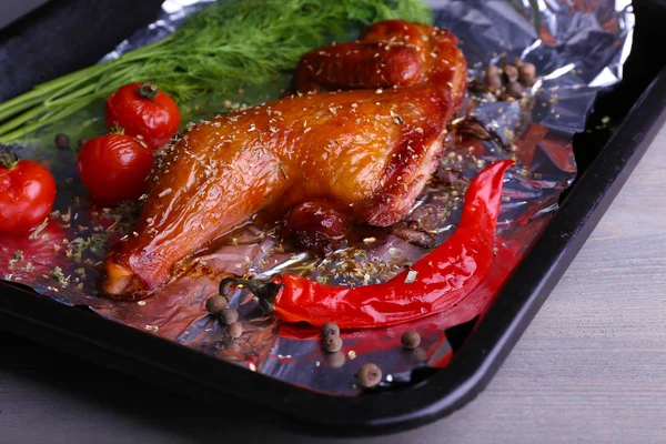 Smoked chicken leg with cherry tomatoes on pan on table close up — Stock Photo, Image