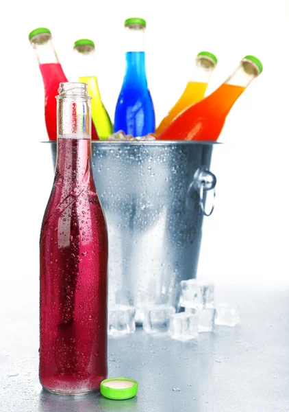 Flaskor av välsmakande dryck i metall hink med is isolerad på vit — Stockfoto