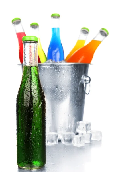Flaskor av välsmakande dryck i metall hink med is isolerad på vit — Stockfoto