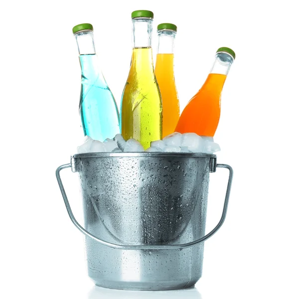 Бутылки вкусного напитка в металлическом ведре со льдом изолированы на белом — стоковое фото