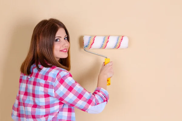 Beautiful woman paints wall in room — Stock Photo, Image