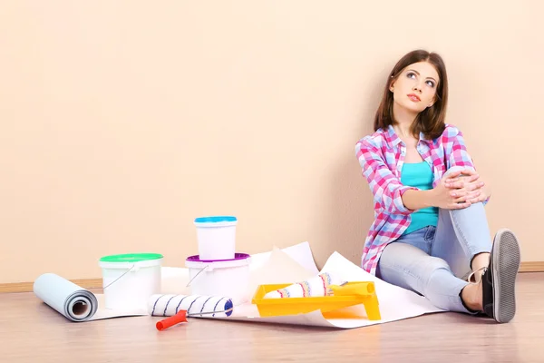 Mooi meisje, zittend op de vloer met apparatuur voor schilderij muur — Stockfoto