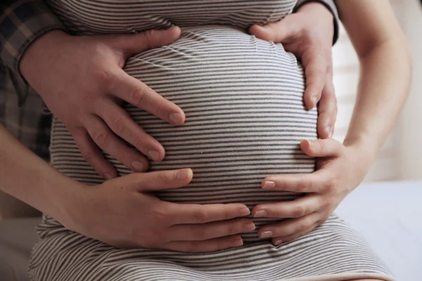 Unga gravid kvinna med man vidrör magen på nära håll — Stockfoto