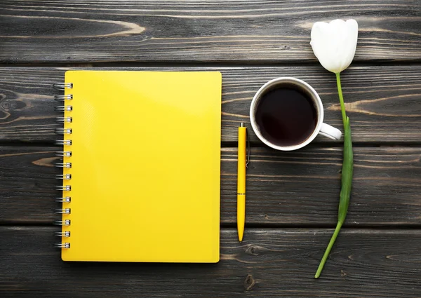 Notebook s šálkem kávy a bílý Tulipán na dřevěné pozadí — Stock fotografie