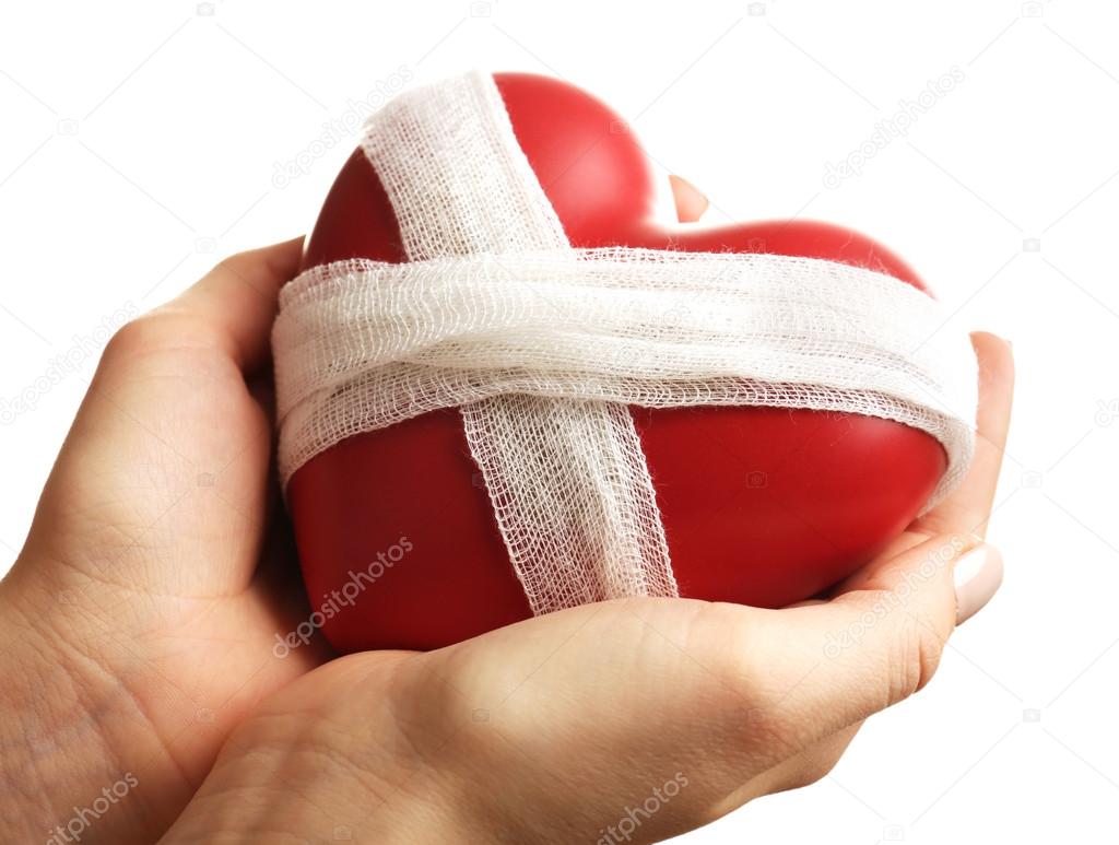Female hands holding bandaged heart isolated on white