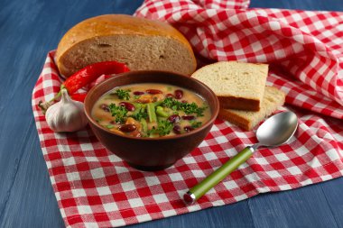 Peçeteye renk ahşap masa arka plan üzerinde taze dilimlenmiş ekmek kase fasulye çorbası