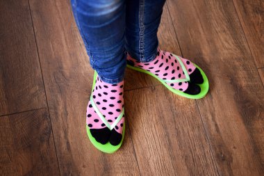 Female feet in socks with pink flip-flops, on floor background clipart