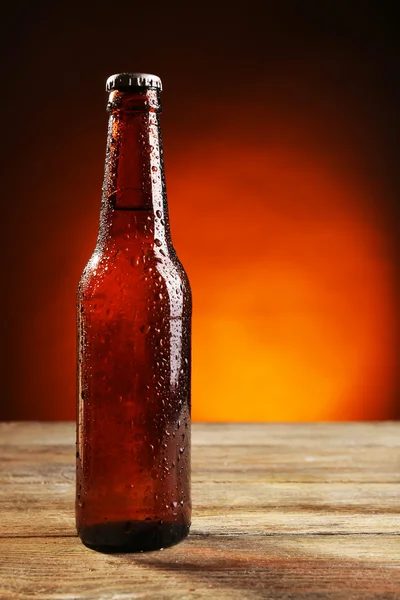 Bottiglia di vetro di birra su tavolo di legno su sfondo di colore scuro — Foto Stock