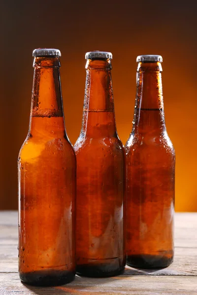 Botellas de vidrio de cerveza sobre mesa de madera sobre fondo oscuro —  Fotos de Stock