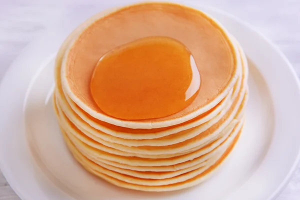 Delicious pancakes with honey on plate on table close-up — Stock Photo, Image