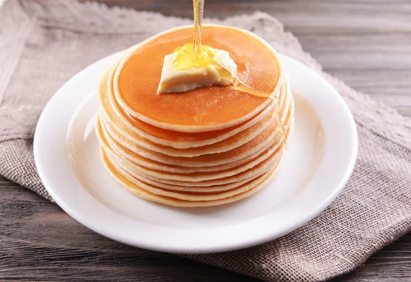 Delicious pancakes with honey on plate on table close-up — Stock Photo, Image