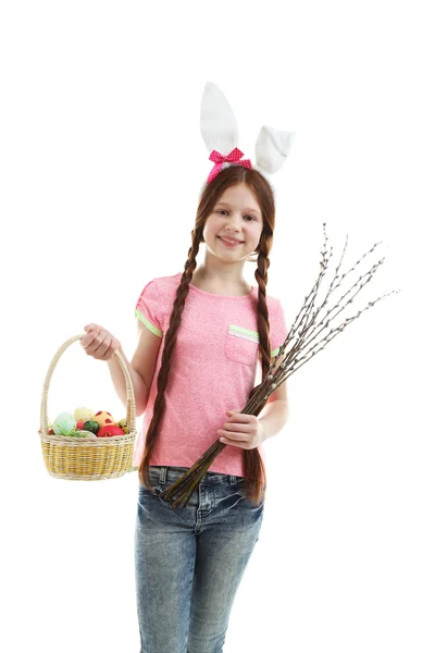 Beautiful little girl holding wicker basket with Easter eggs and pussy-willow branches, isolated on white — Stock Photo, Image