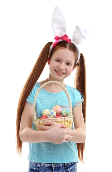 Mooi meisje dragen Easter bunny oren en houden rieten mand met Pasen eieren, geïsoleerd op wit — Stockfoto