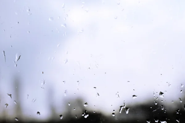 Gotas de lluvia en la ventana de cristal con vistas a la calle en el fondo — Foto de Stock