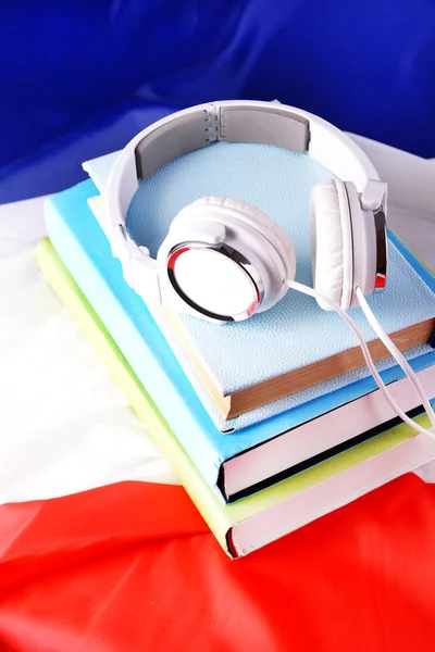 Книги и наушники на фоне французского флага — стоковое фото