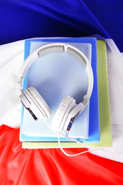 Книги и наушники на фоне французского флага — стоковое фото