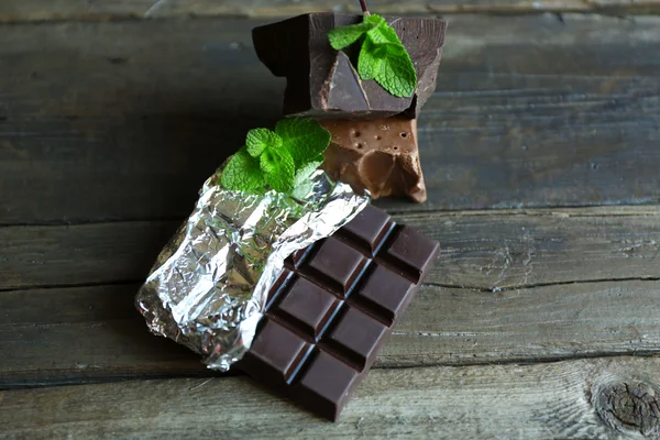 Delicioso chocolate com folhas de hortelã em fundo de madeira — Fotografia de Stock