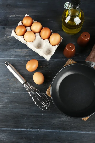 Still life with eggs and pan on wooden table, top view — Stock Photo, Image