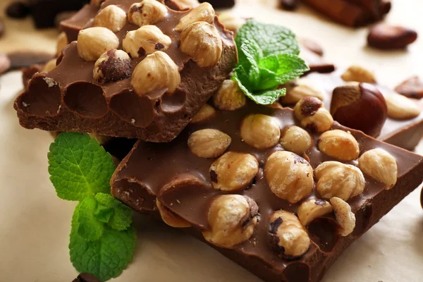 Čokoláda s ořechy, koření a máta na papíře, detail — Stock fotografie